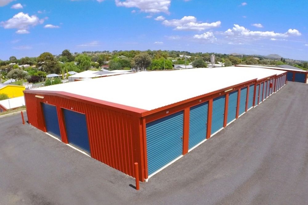 High angle view of a red self storage facility with rows of blue roller doors under a blue sky-